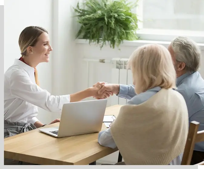 A woman shaking hands with another person at a table.