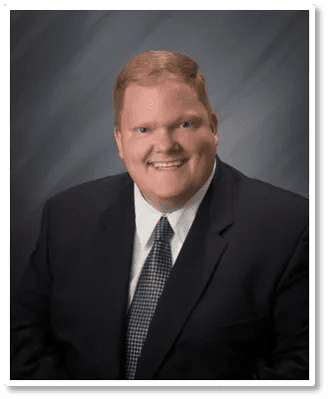 A man in a suit and tie smiling for the camera.